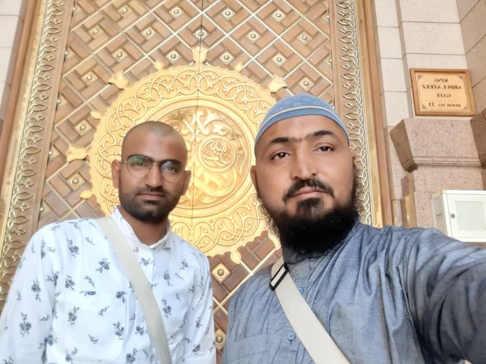 Two pilgrims at one of the golden doors of Masjid an-Nabawi